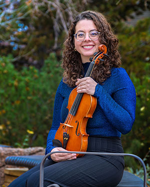 woman sitting outside holding a violin