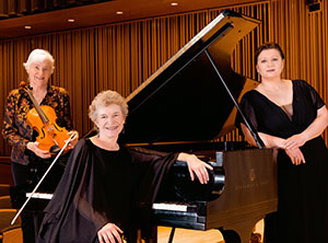 three people gathered around a grand piano