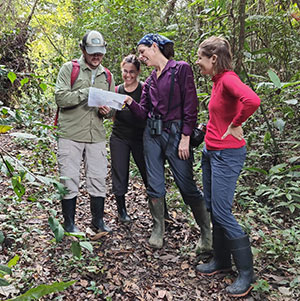 four people looking at a map in a forest