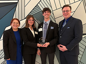 four people posing with a trophy