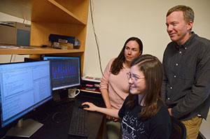 three people looking at a computer screen