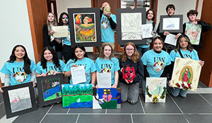 group of teenagers holding up artwork