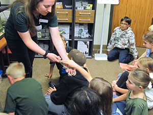 a person showing a snake to a group of children