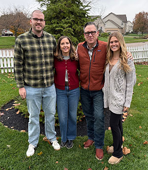 Four people posing together on a lawn