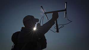silhouette against the sky of person holding up a tracking device