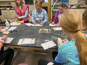 group of young people around a table with papers on it