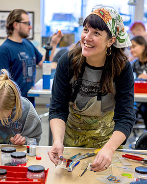 woman at table in a busy room working with art supplies