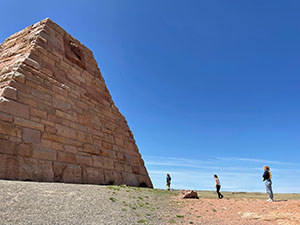 people beside a large sandstone pyramid-shaped structure