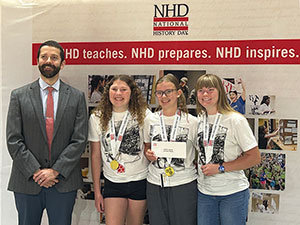 a man and three teenage girls posing in front of a banner