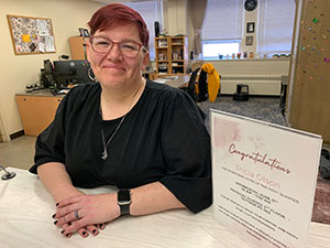 woman at a desk with an award certificate beside her