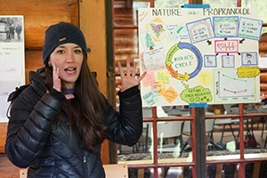 woman presenting information with a poster displayed beside her
