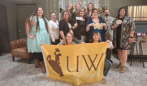 group of people posing for this photo and holding up a UW flag