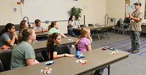 young people sitting at tables listening to someone speak