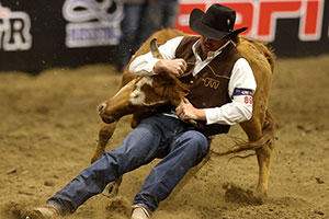 man wrestling a steer in an arena