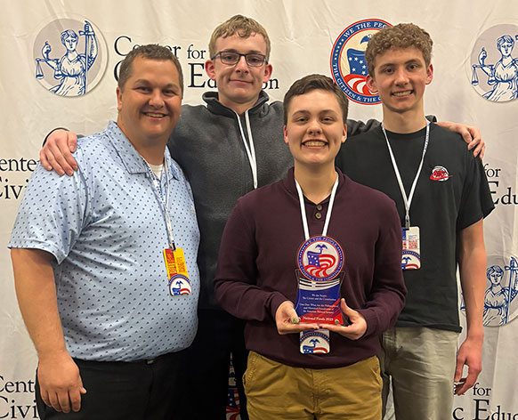 four people posing with an award