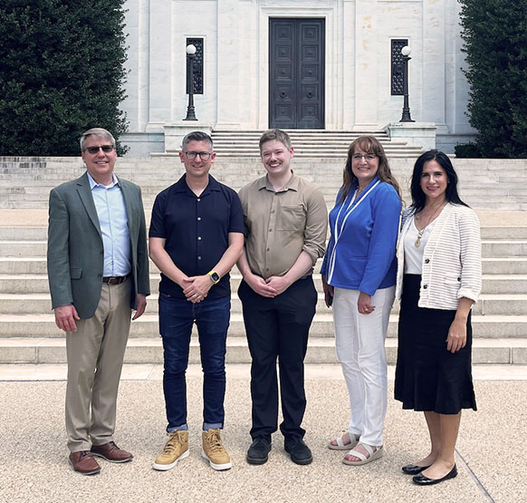 five people posing in front of the steps to a building