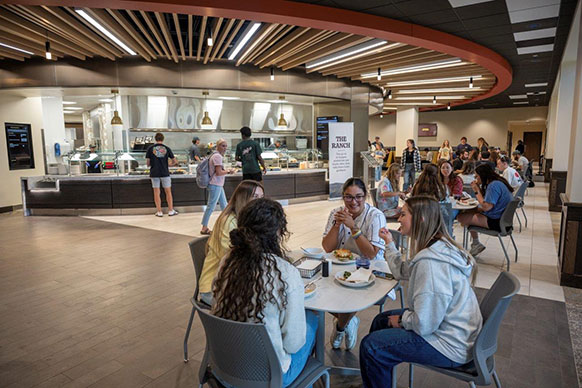 people at a table with food service areas in the background