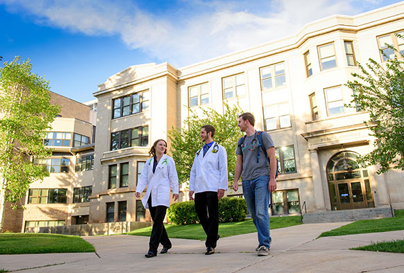 three people walking in front of a large building