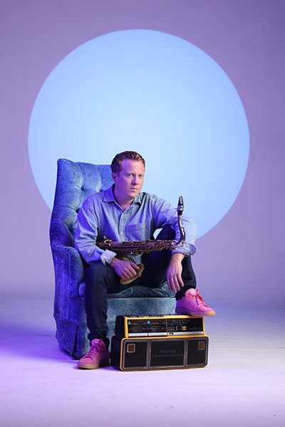 man sitting and holding a saxophone