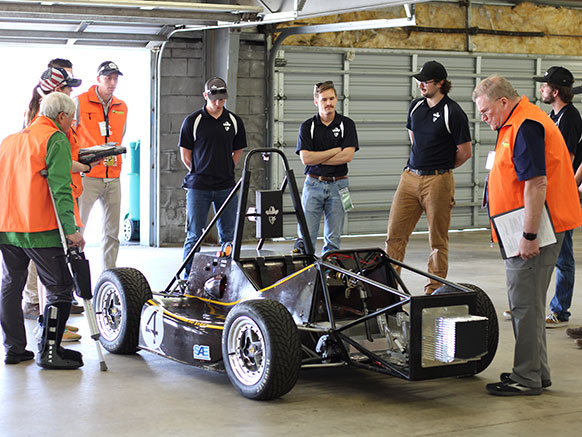 people standing around a small race car
