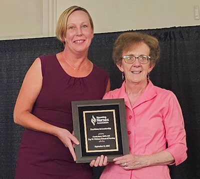 two women posing together with an award plaque