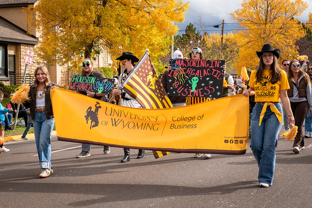 people walking in a parade holding a banner between them
