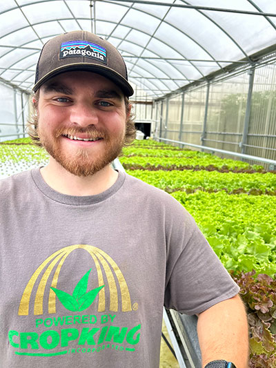 man standing with a greenhouse in the background