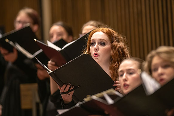 people holding folders of songs and singing
