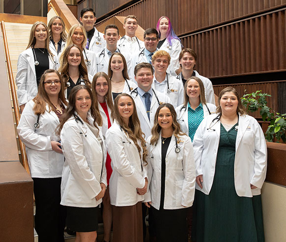 people in white medical coats posing on a staircase