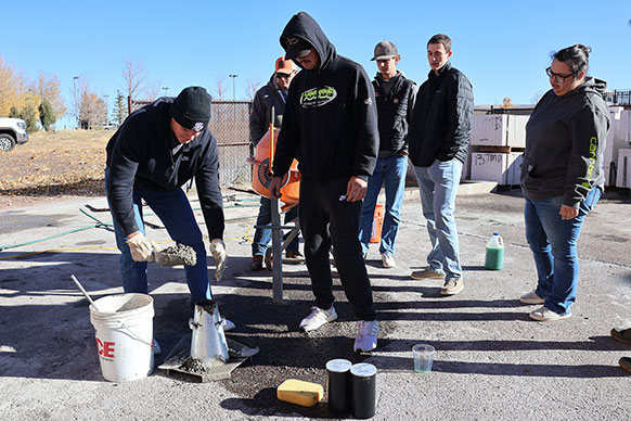 person putting cement into a cone mold while others look on