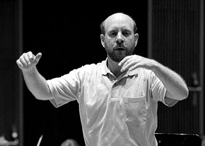 man with arms raised to conduct an orchestra