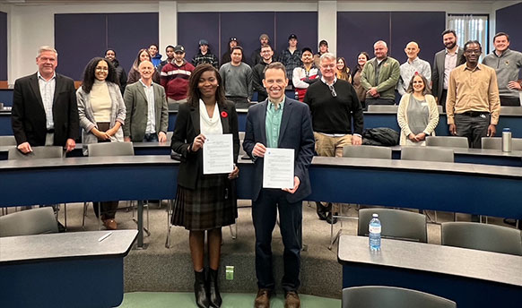 two people holding papers with people standing behind them