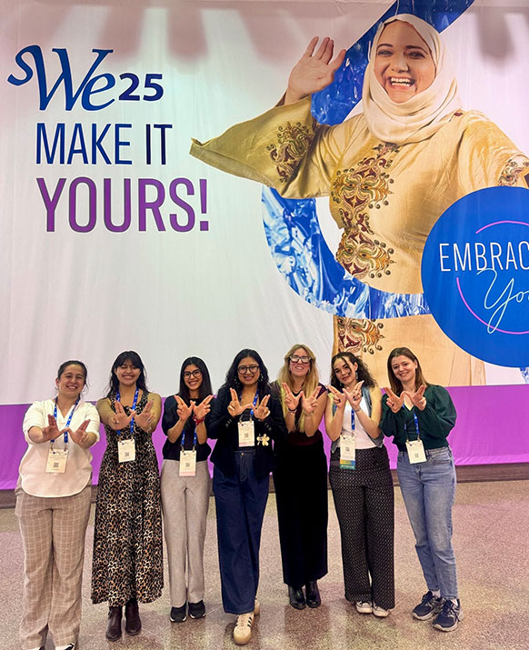 women standing together in front of conference banner