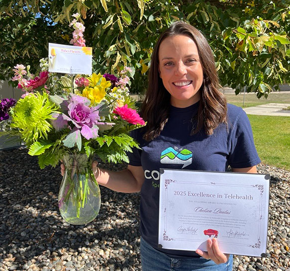 woman holding flowers and an award certificate