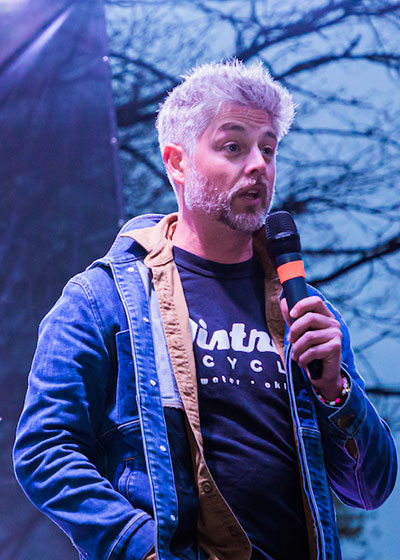 man with a microphone speaking outdoors
