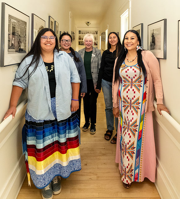 people posing in a hallway lined with pictures on the walls