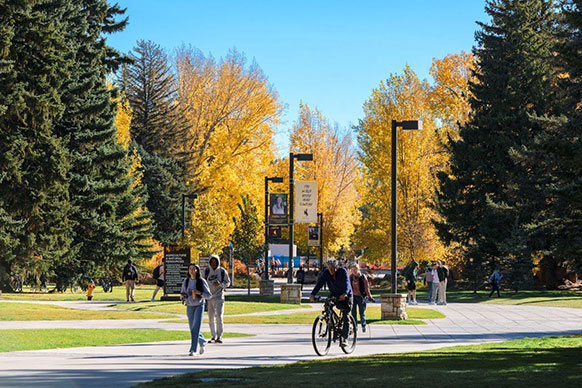 people walking and riding bikes on campus in the autumn