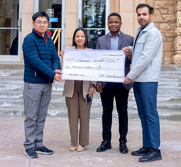 four people holding an oversized check