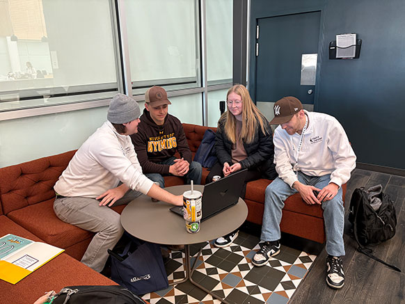 group of people looking at a computer on a small table