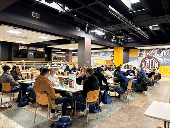 people eating at tables in a large dining hall