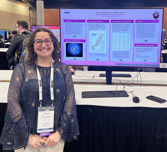 woman standing beside a computer monitor displaying her project