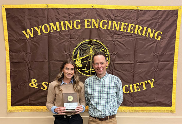 woman holding an award while standing next to a man