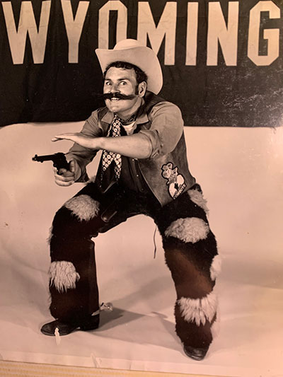 black and white photo of a man in a cowboy costume pretening to shoot a revolver