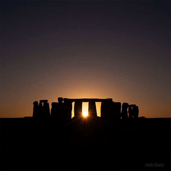 sunrise silhouetting Stonehenge