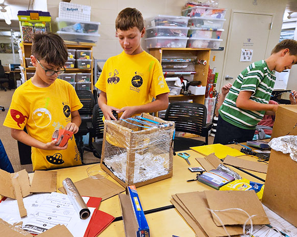 middle school students making things with boxes and plastic wrap