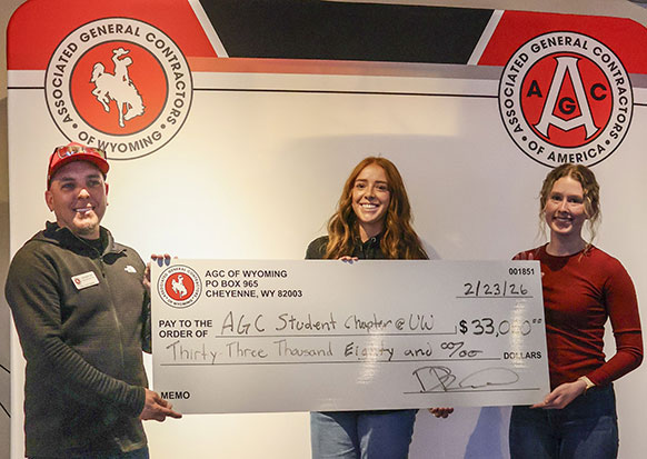 three people posing with an oversized check