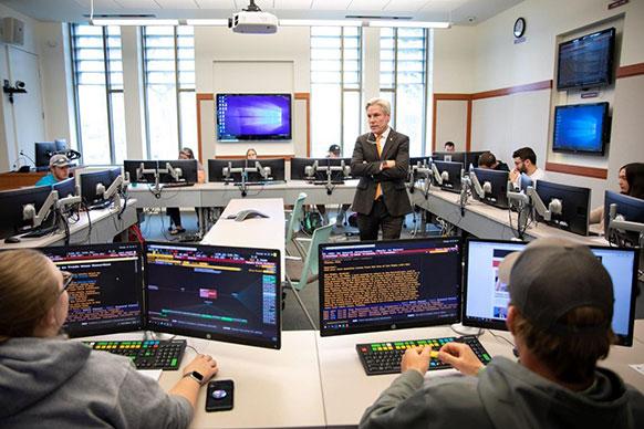 man lecturing in a classroom with people at computers