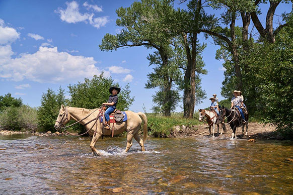 people riding horses through a stream