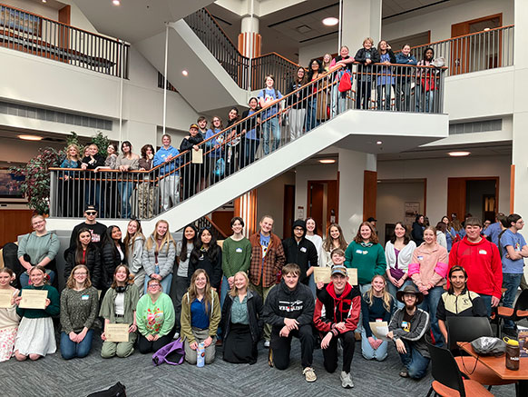 large group of students posing down a stairway and below it