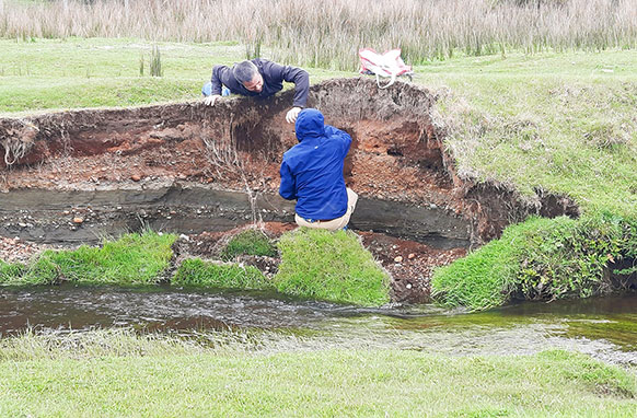 people examining a creek bank